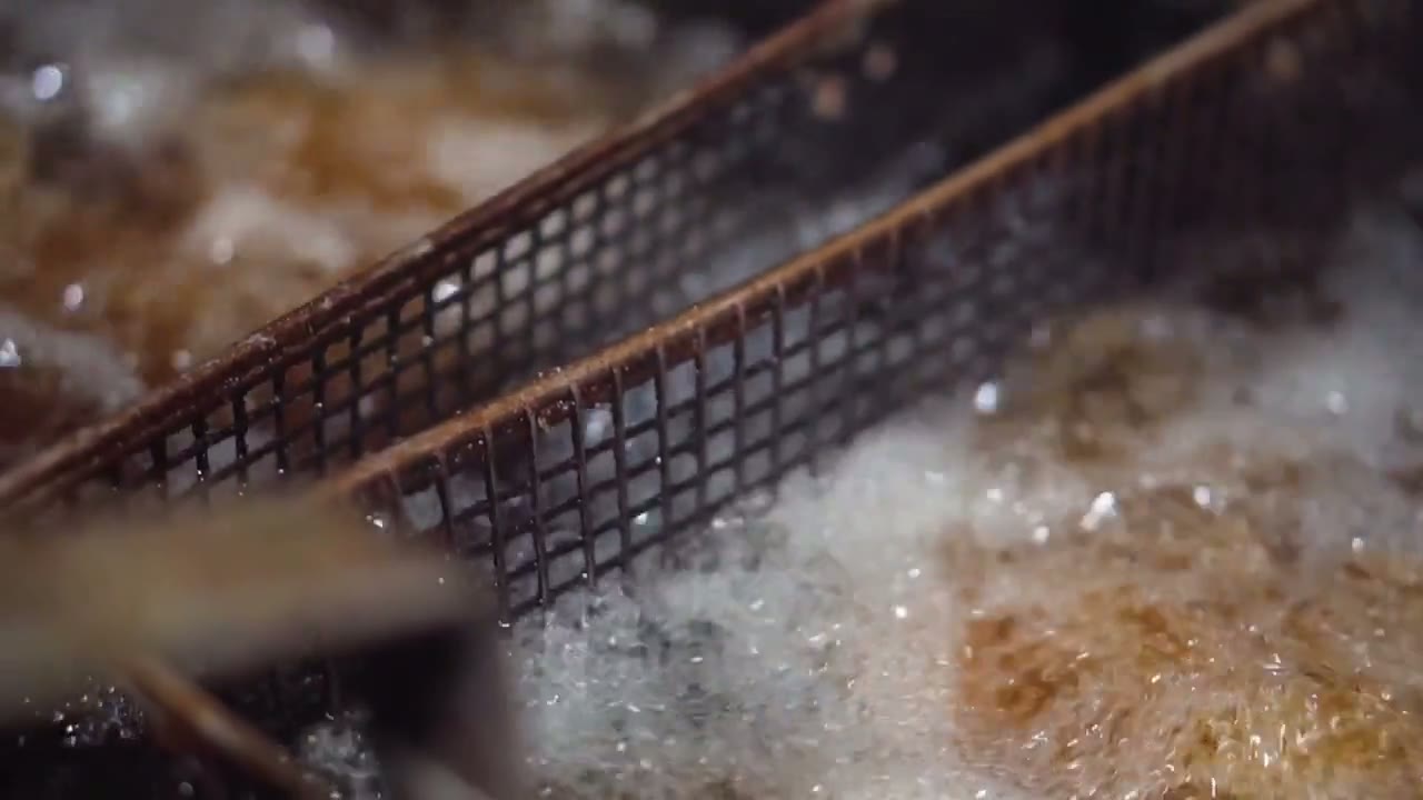 Commercial fryer baskets cooking food in hot oil